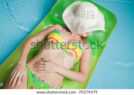 Beautiful young woman lies  on an inflatable mattress in the pool. Vacation.