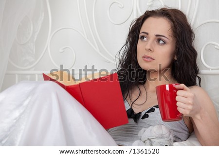 Young beautiful woman reads book in bedroom.