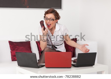 Stressed  young businesswoman with telephones in her hands.