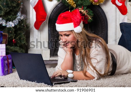 Young woman with notebook lying near Christmas tree at home.