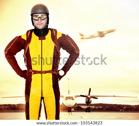 A picture of a young parachutist standing in front of a plane at the apron
