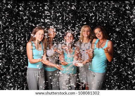 A picture of five girl friends throwing feather all around black background