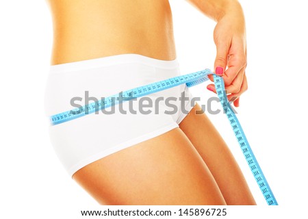 A picture of a young fit woman checking her hip measurements over white background
