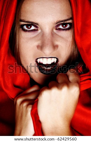 Woman vampire showing her fang and covered in red