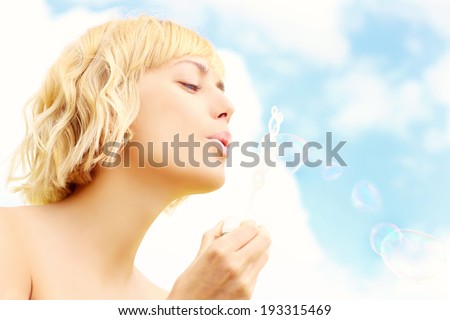 A picture of a beautiful woman blowing soap bubbles over sky