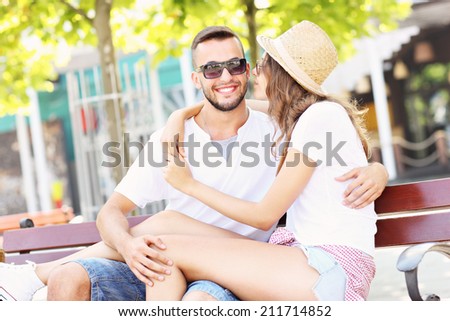 A picture of a joyful couple kissing on a bench