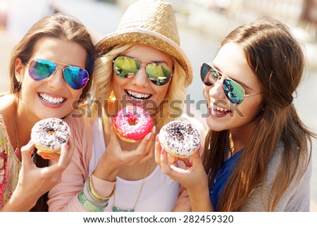 Group of friends eating donuts in the city