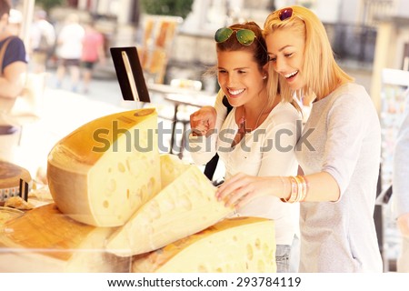 A picture of two tourists shopping for cheese on a food market