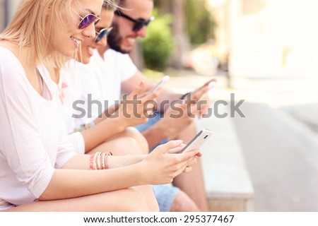 A picture of a group of friends using smart phones in the city