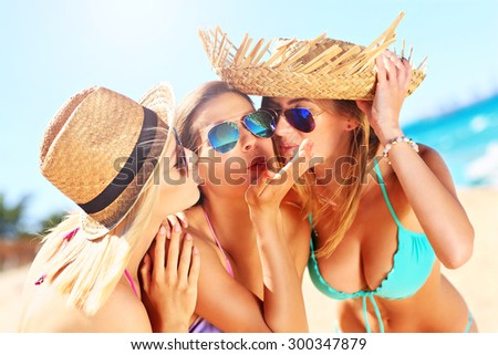 A picture of two women kissing a friend on the beach party