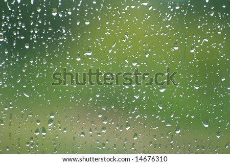 Rain drops on a window pane,  green blurry background