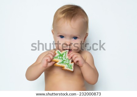 portrait of adorable beautiful funny emotions baby girl eating cookie of christmas tree form