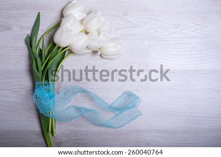 spring flowers white tulips bouquet on wooden background with blue lace ribbon present for holidays mother day easter valentines
