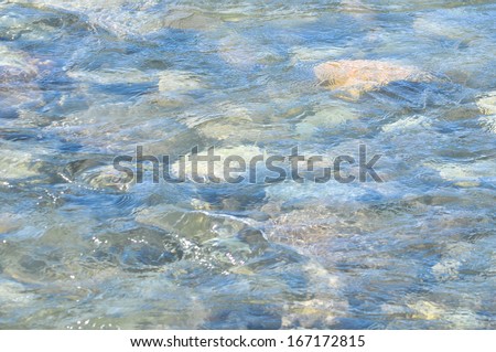 Yakutsk river in the mountains. Photo texture the surface of the transparent water flowing against the background of multicolored pebbles on the bottom.