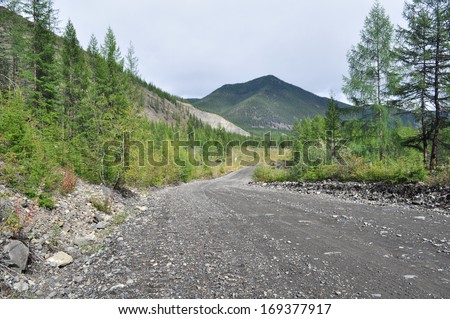 Soil highway in Yakutia. Cloudy landscape on a route Yakutsk - Magadan. Russia. mountains