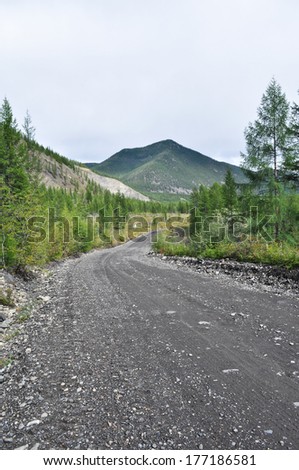 Soil highway in Yakutia. Cloudy landscape on a route Yakutsk - Magadan. Russia. mountains