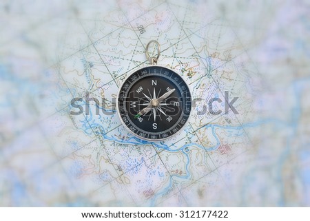 Magnetic compass is located on a topographic map. Navigation: a compass and a map.