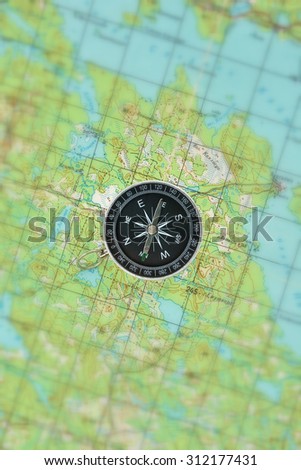 Magnetic compass is located on a topographic map. Orienteering in the wilderness