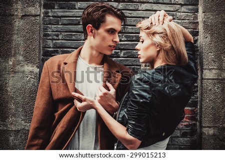 Young and trendy man and woman in passion emotions of the street with brick walls. Fashion style