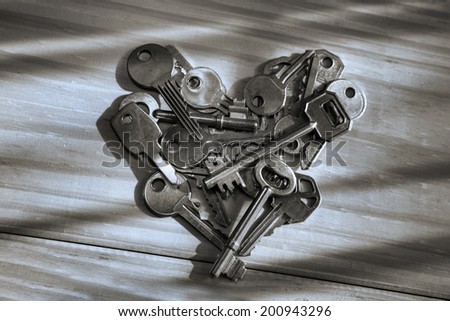Old keys in a heart shape, on a wood surface with natural window light, vintage look