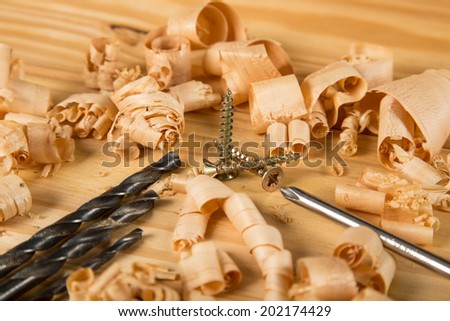 carpenters table with screws, drill bits, wood shavings and a screw driver
