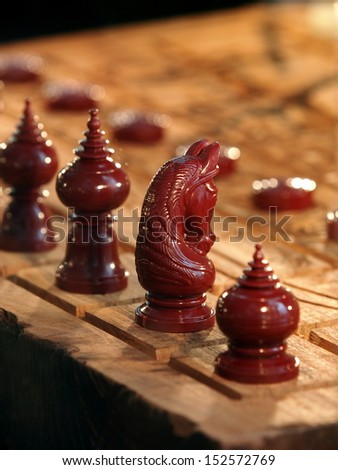 nice plastic Thai chess figures red with artistic decorative ornaments on a wooden hand cut chessboard