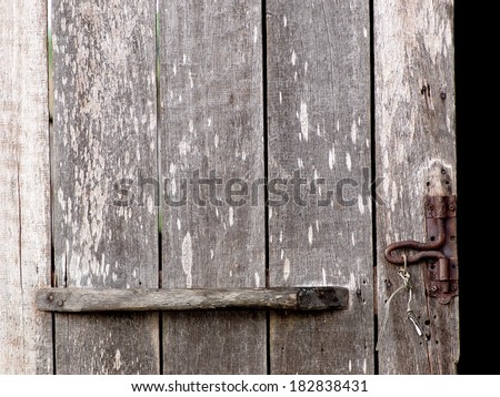 old aged weathered wood surface of an old country house door with wooden grip and rusty bolt.