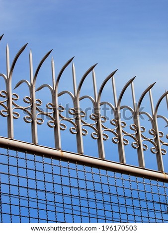 home metal fence with mesh iron wires and old vintage style long sharp spikes on the top