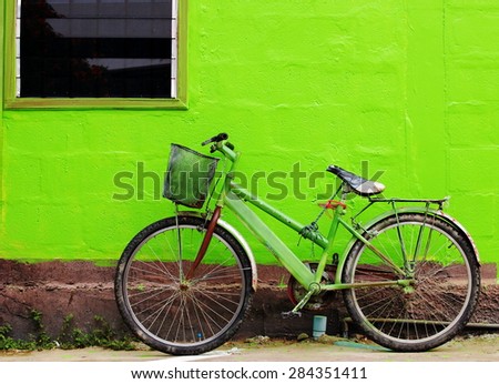 old retro style vintage family bicycle parking at a bright green painted house with glass window on a sunny day in a traditional and cultural tourist attraction province, NAN, THAILAND