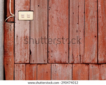 old aged abandoned weathered wood surface of a red brown color old country house external wall with white plastic electric switches installed