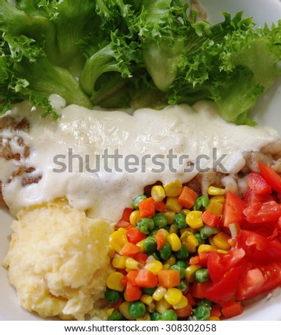 clean food menu of fish fillet with white sauce green mixed salad yellow potato red tomato carrot and broccoli