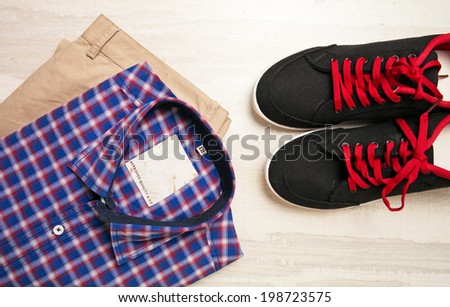a pair of pants, a checked shirt and casual canvas shoes on old background