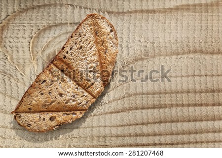 Slice of toasted Integral Brown Bread, placed on roughly treated, coarse Pine wooden table surface.