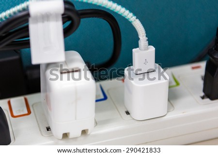 Power cord with several adapters and chargers for various electronic devices in a paperless office