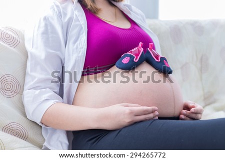 Pregnant woman with baby shoes on her belly