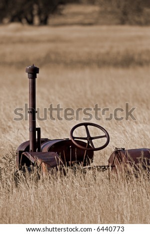 Rusty antique tractor in tall prairie grass.