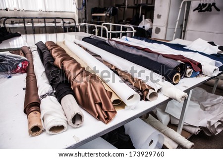 a table with rolls of cloth of various colors in a factory