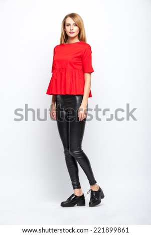 beautiful young blonde woman in red blouse standing on grey background