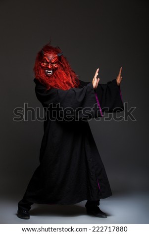 halloween monster with red face on dark background, pushing something