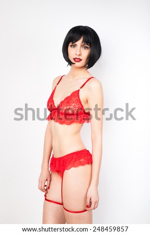 sexy young brunette woman with red lips wearing red lingerie with garters on white background