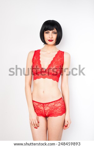 sexy young brunette woman with red lips wearing red lingerie and being natural on white background