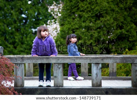 Young sisters stop on a bridge in the park to rest and enjoy the view