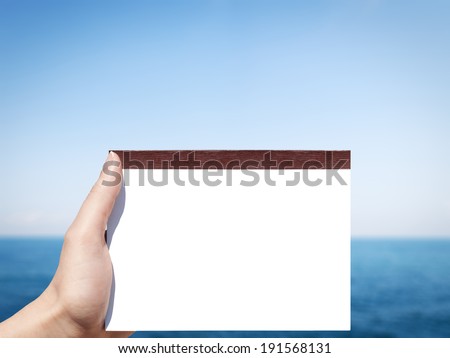 horizontal white blank notebook in woman hand with sea background