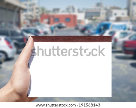 white blank horizontal notebook in woman hand and cars background