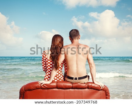 couple resting on leather couch on the beach