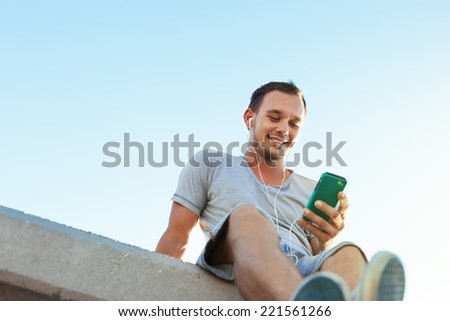 young and handsome man with mobile smartphone sitting on the bench