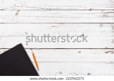 white blank wooden table with dark notebook and pencil in the corner, top view