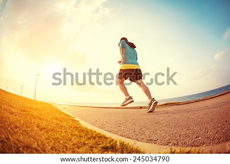 athletic sportsman running in the park near the ocean in the evening in sunset