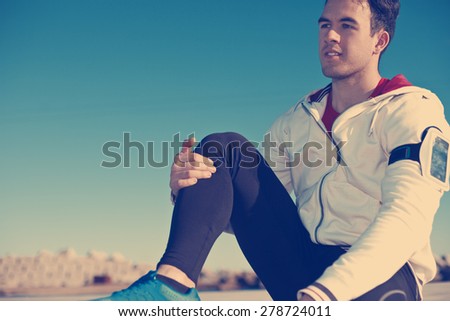 young athlete with armband relaxing after fitness outdoors (intentional vintage color)