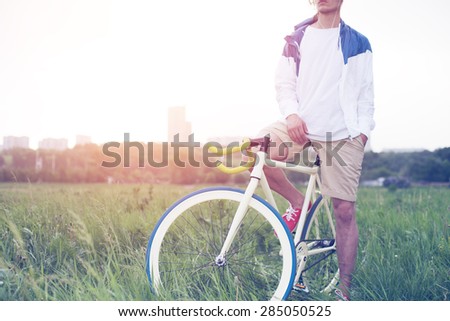 young man in blank t-shirt sitting on his bicycle in the field (intentional sun glare and vintage colors)